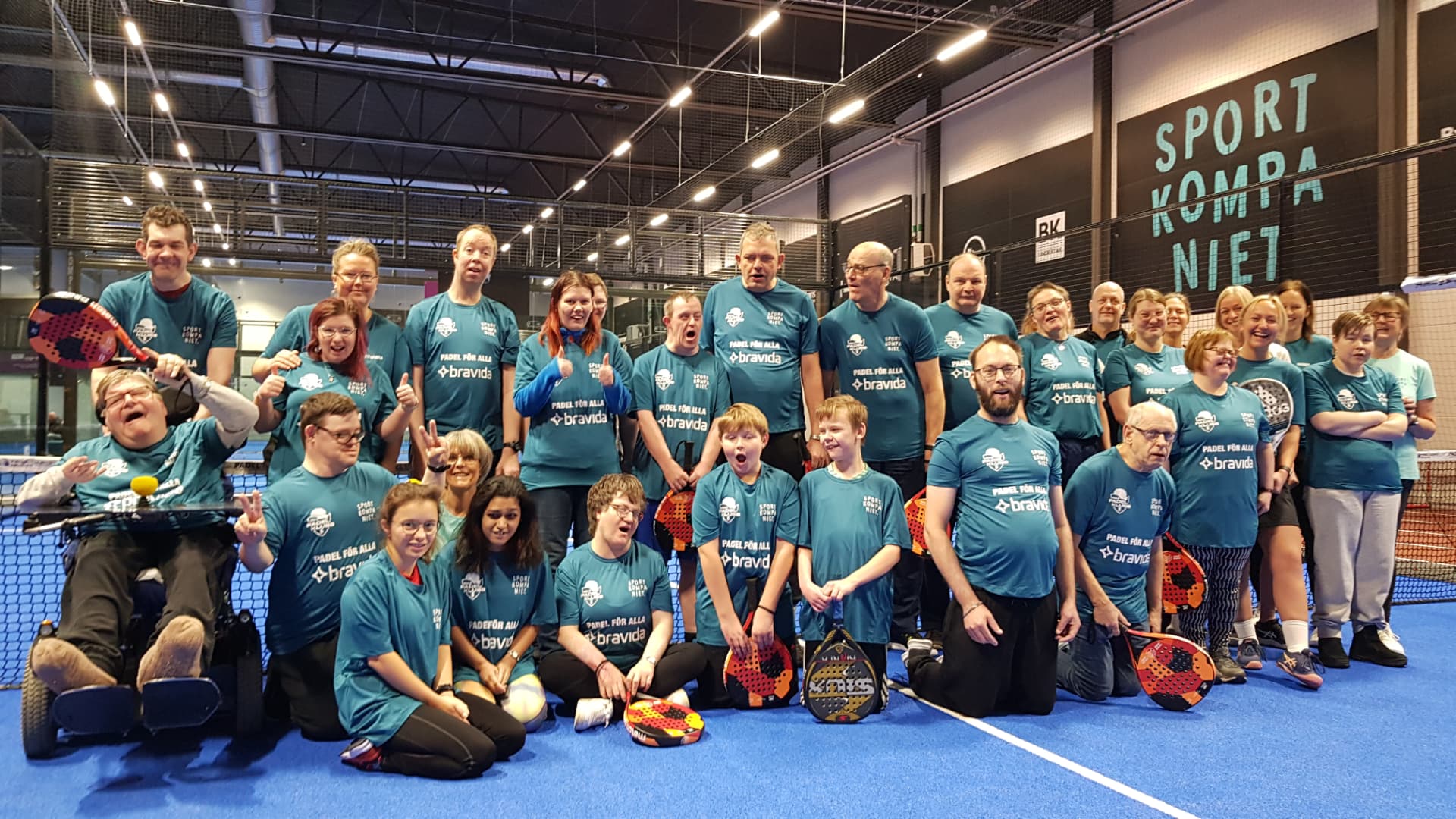 Deltagare och volontärer i Padel för alla samlade på padelbanan på Sportkompaniet